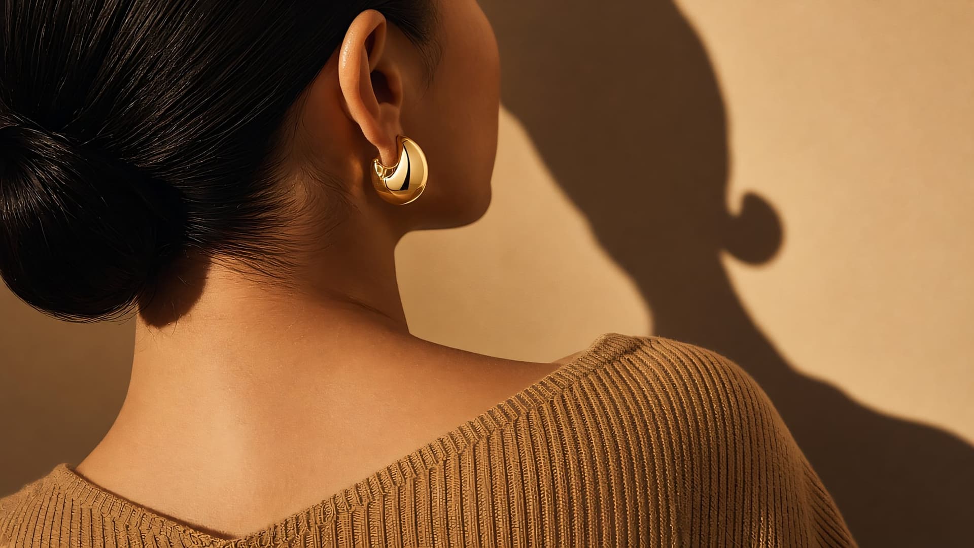 Model in profile wearing a gold dome hoop earring