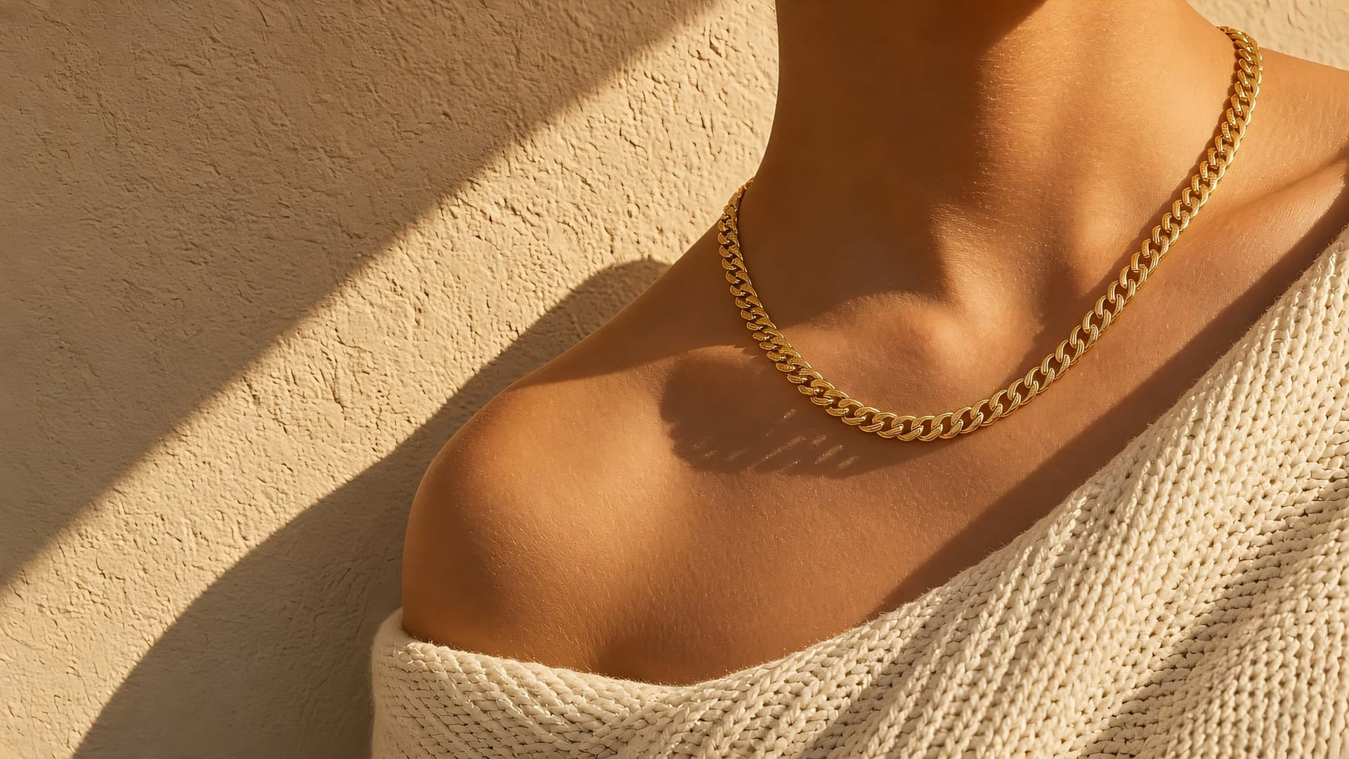 Model wearing stacked gold rings and fine gold chains